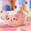 Plush toy resembling a cupcake with rabbit ears and a bow on a colorful background