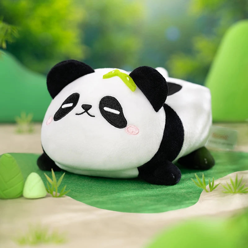 Plush panda toy sitting on a green surface with a blurred natural background