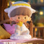 Toy figure of a sheep with a yellow hat and star, sitting on a bed with blurred background