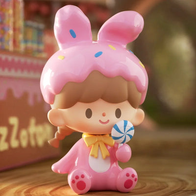 Toy figure with pink hair and dress holding a lollipop, blurred background