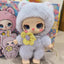 Plush toy with a gray hood and yellow bow in front of colorful packaging