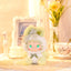 Plush toy with green hair and outfit on a decorative surface with 'Lovely Emma' branding.